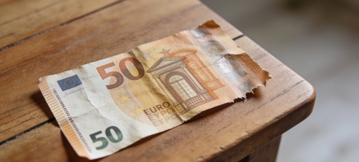 Un billet de 50 euros usagé posé sur une table en bois.