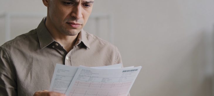 Homme tenant documents medicaux avec expression préoccupée