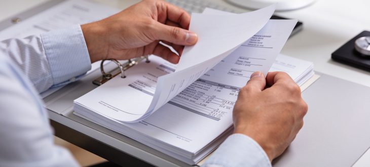 Personne consultant documents financiers sur bureau organisé.