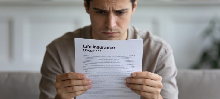 Personne lisant document d'assurance vie avec expression préoccupée.