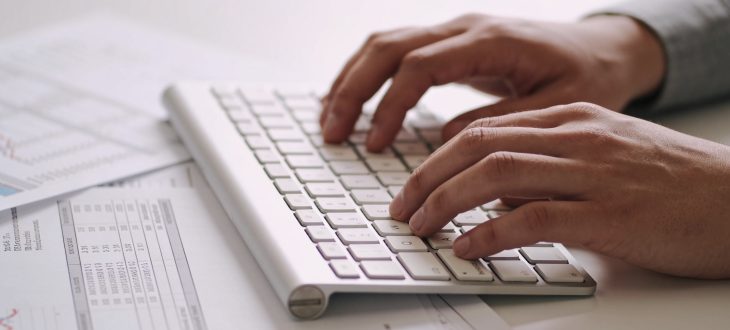 Personne tapant sur clavier avec documents financiers visibles.