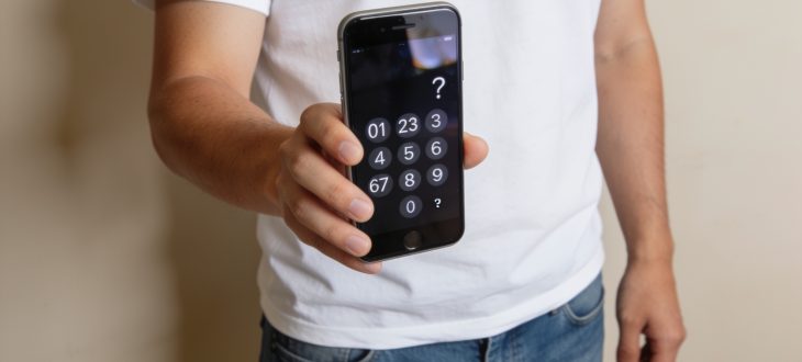 Personne tenant telephone affichant numero avec point interrogation.